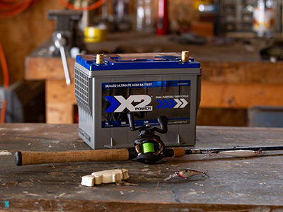 X2Power boat battery on a table with a fishing rod in front