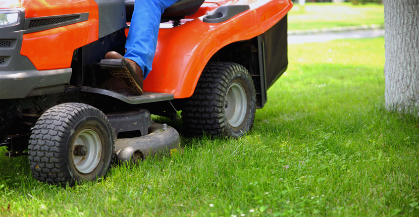 Angled side view of an orange and black riding lawn mower