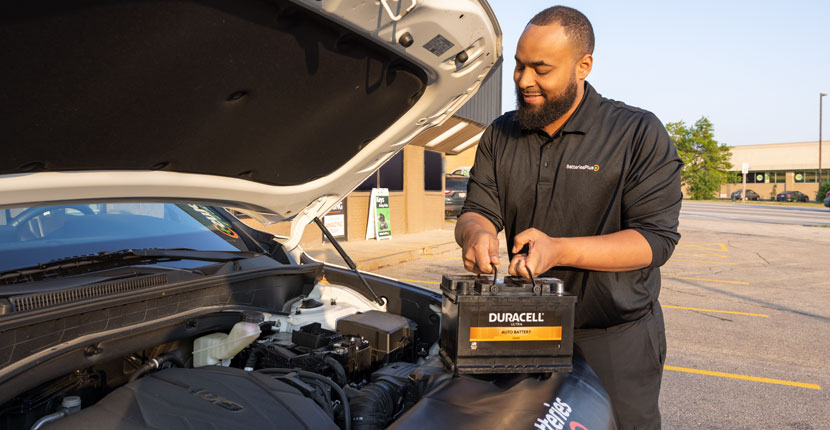 Employee replacing a battery in a vehicle