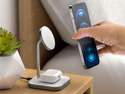 Person placing a phone on a MagSafe wireless charger with AirPods charging on the base