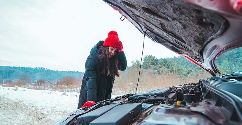 Young adult wearing read hat and gloves looking at the engine