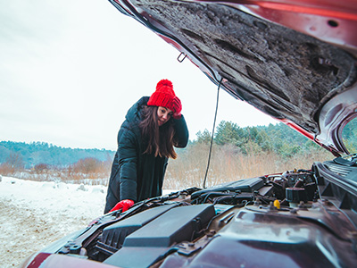 Young adult wearing read hat and gloves looking at the engine