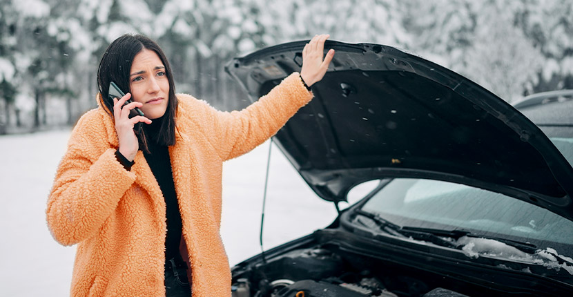 Woman in orange jacket on phone with car hood up